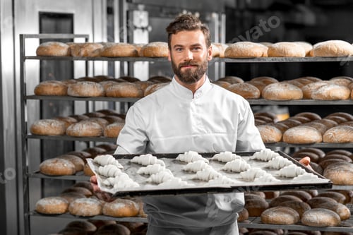 Preview: Handsome baker holding tray full of freshly baked croisants