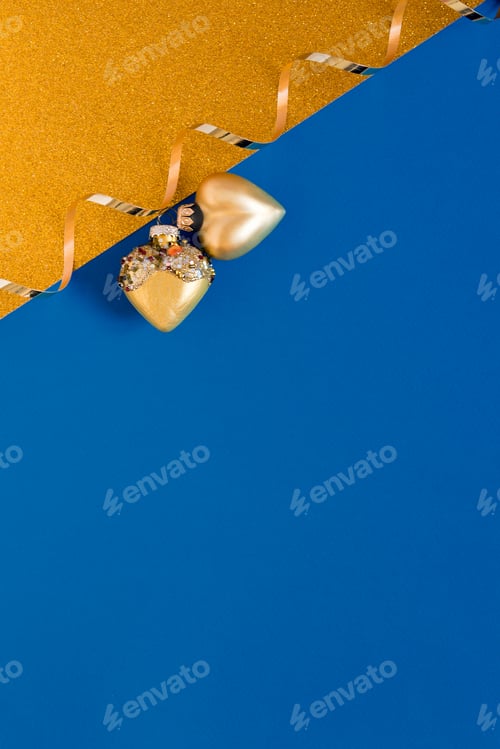 Preview: New Year's card in blue and gold. Christmas toys hearts and gold ribbon. Flat lay with copy space.