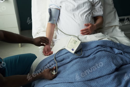 Preview: Pregnant Woman Lying in Hospital Bed Having Blood Pressure Checked