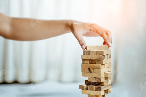 Preview: hand pulling out or placing wood block on the tower in modern office. plan and strategy in business