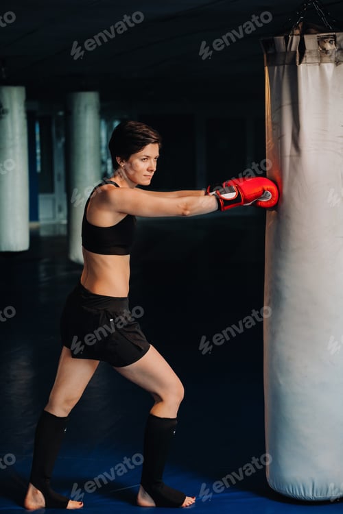 Preview: portrait of a female boxer in red gloves in the gym during training