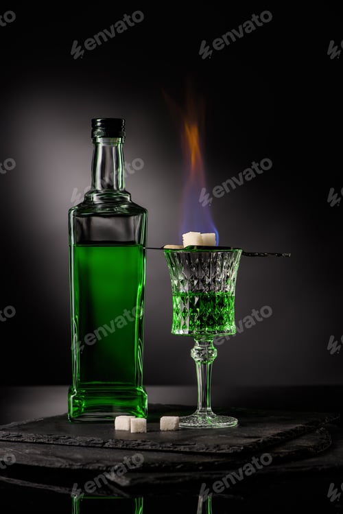Preview: close-up shot of spoon with sugar cubes over burning absinthe in glass on dark background