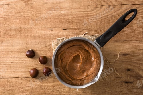 Preview: Chestnut cream in saucepan on wooden table with chestnuts aside