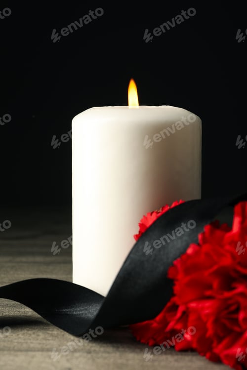 Preview: Candle, flowers and black ribbon on wooden table on black background