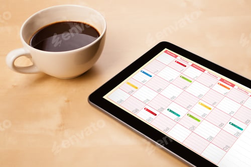 Preview: Workplace With Tablet Pc Showing Calendar And A Cup Of Coffee On A Wooden Work Table Close-Up