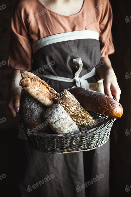 Preview: French baguettes in female hands on a black background. homemade baking