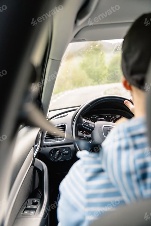 Preview: Man driving car while being on a day road trip.