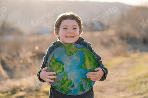 Preview: Little boy holding planet in hands against green spring background. Earth day
