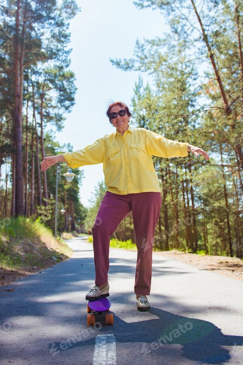 Preview: Stylish elderly woman having fun on a skateboard outdoors