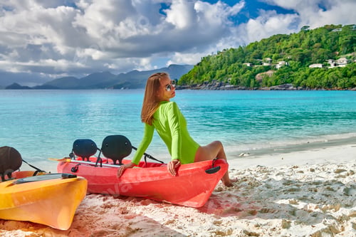 Preview: Woman Sitting On Kayak. Beautiful Petite Anse Beach With Palm Tree At Seychelles, Mahe