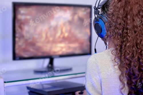 Preview: Rearview shot of a woman wearing a headset while playing video games