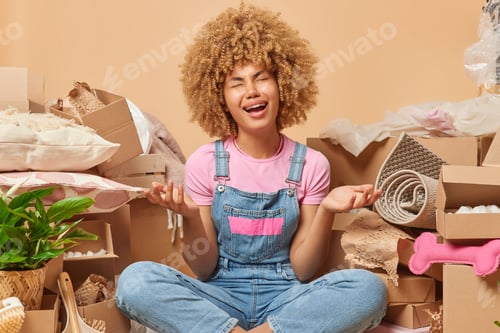 Preview: Upset depressed curly haired woman dressed in casual tshirt and denim overalls cries from despair