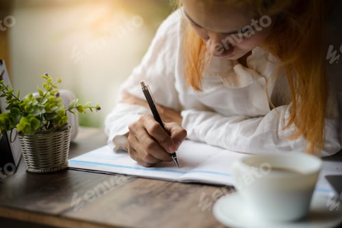 Preview: Woman Writing in Calendar at Desk with Coffee