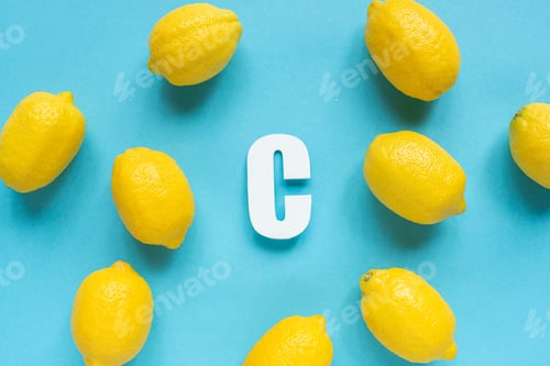 Preview: top view of ripe yellow lemons and letter C on blue background