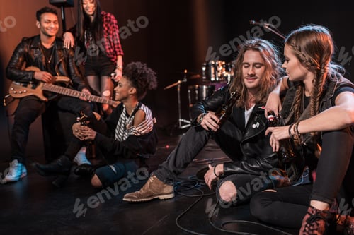 Preview: Young rock and roll band drinking beer after concert on stage