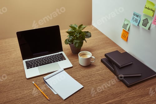 Preview: high angle view of laptop, notebooks and pencil on wooden tabletop, stickers on wall