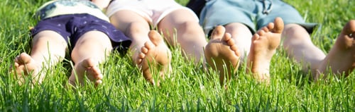 Preview: Children's legs on green grass. Selective focus.