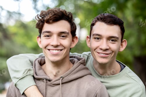 Preview: Twin brothers embracing outdoors with genuine smiles