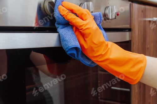 Preview: Hand with a microfiber cloth is being wiped on the outside of the electric oven.