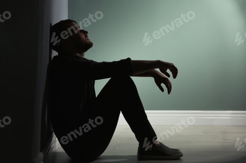 Preview: Depressed young man sitting on floor in darkness