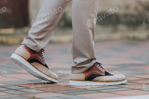 Preview: Close-up shot of a man wearing sneakers with beige classic pants
