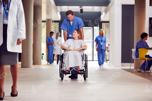 Preview: Male Nurse Wearing Scrubs Pushing Female Patient In Wheelchair Through Hospital Building