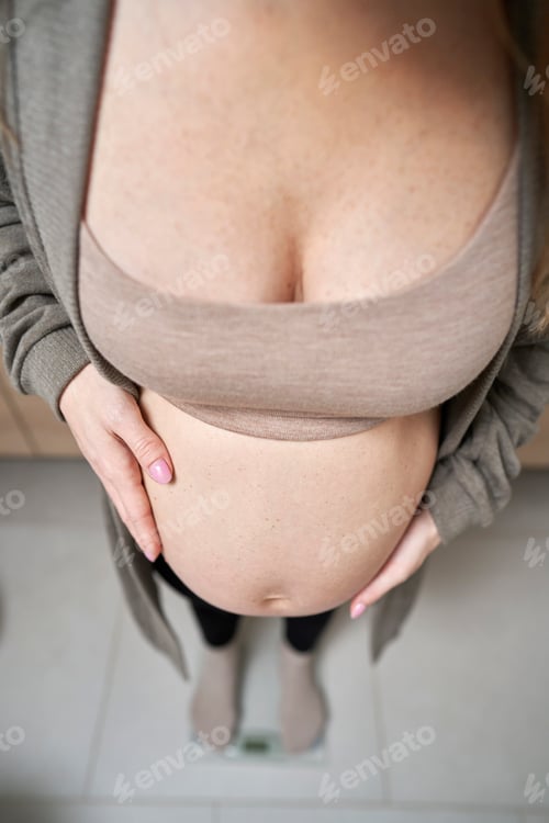 Preview: Pregnant woman standing on bathroom scale