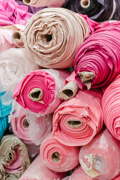 Preview: Vibrant collection of multicolored fabric rolls and swatches, arranged in a neat pile