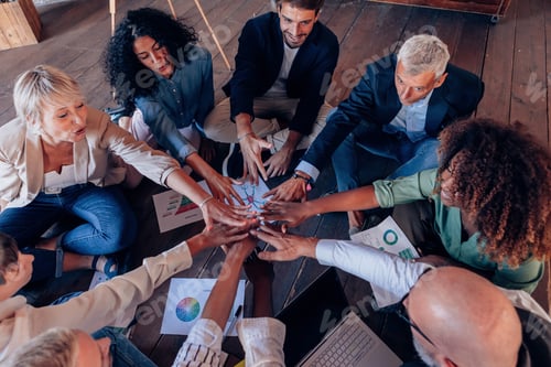 Preview: group of people working in team sitting on circle on floor with positive vibes
