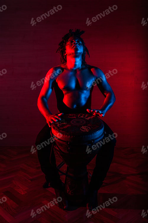 Preview: African American man playing Djembe drum in studio