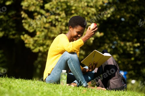 Preview: young african american woman witting in park reading book
