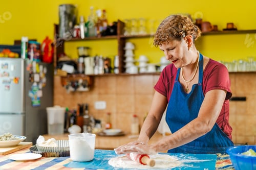 Preview: Senior woman making dough with rolling pin in kitchen