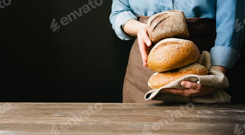 Preview: Woman holds in her hands lot of rolls of fresh bread . Rustic home bakery style