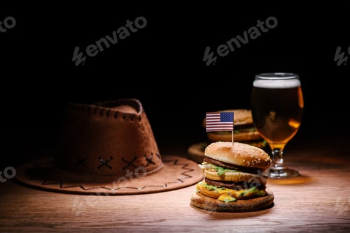 Preview: delicious burger on wooden table with american cowboy hat and glass of beer