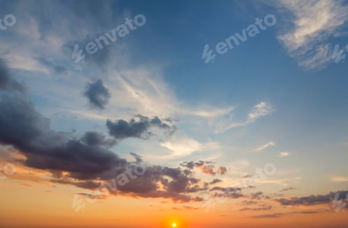Preview: Panorama of sky at sunrise or sunset. Beautiful view of dark blue clouds lit by bright orange yellow
