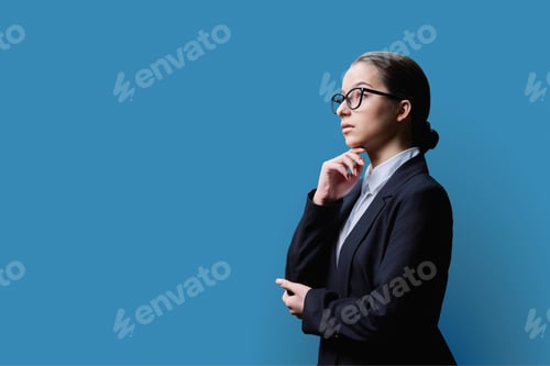 Preview: Profile view, portrait of serious young teenage female on blue background, copy space