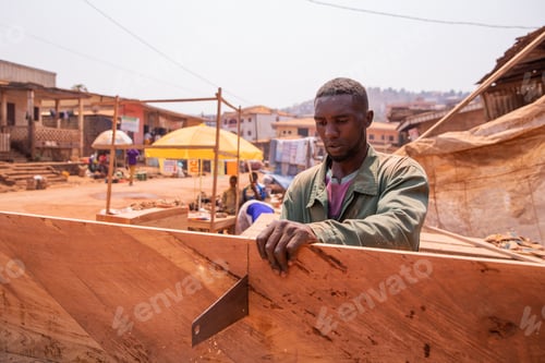 Preview: A carpenter cuts a board with a hand saw in his workshop in Africa