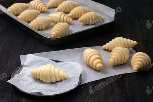 Preview: Raw Unbaked Croissant on Baking Paper in Rustic PlateOver Black Wooden Table