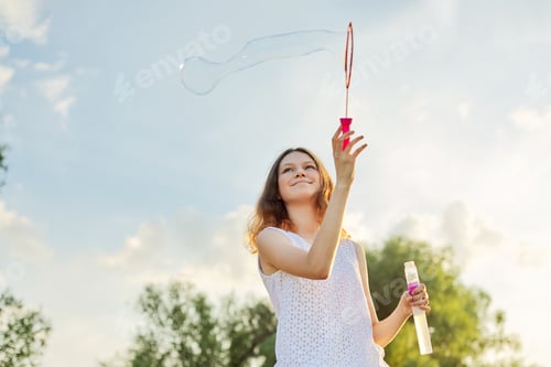 Preview: Happy cheerful smiling girl teenager 15, 16 years old with soap bubbles