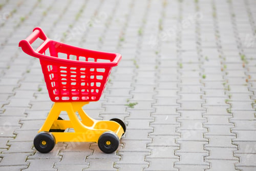 Preview: Bright plastic colorful shopping cart toy outdoors on sunny summer day.