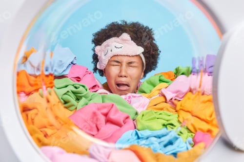 Preview: Frustrated disappointed curly haired tired woman cries from tiredness wears blindfold on forehead wa