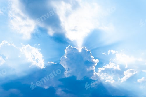 Preview: A vibrant blue sky and sunlight streams out from behind a central, larger cloud.