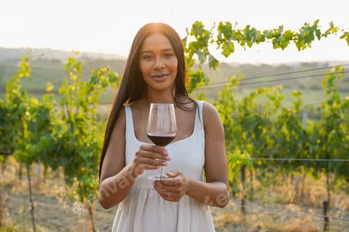 Preview: Beautiful woman looking on camera during wine tasting at vineyard