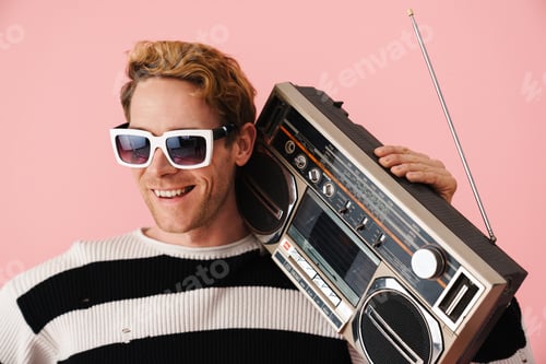 Preview: Ginger young man wearing sunglasses posing with retro tape recorder