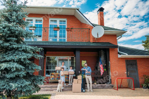 Preview: family with cardboard boxes and labrador dog standing on country house porch, moving home concept