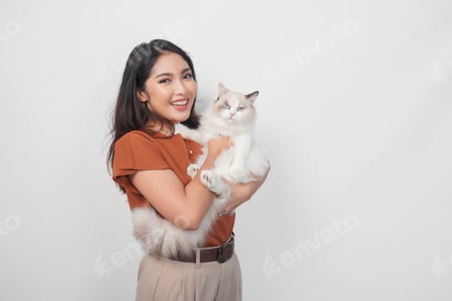 Preview: Portrait of young Asian woman in brown shirt holding her ragdoll cat and smiling to the camera.