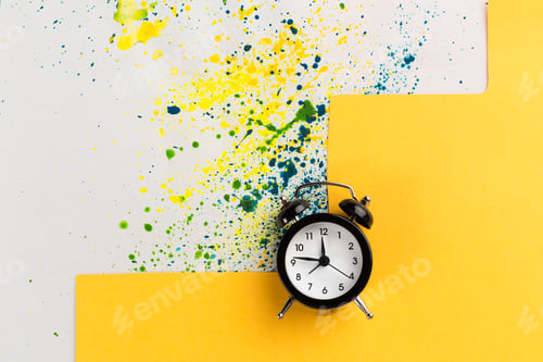 Preview: Vintage alarm clock on a creative colorful background with paint sprinkles