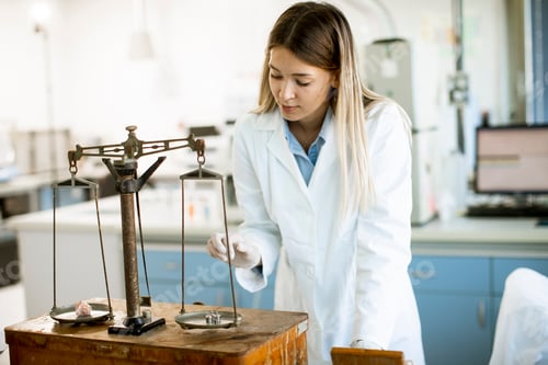 Preview: Young female researcher measuring weight of the mineral sample in the lab