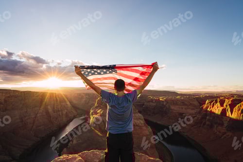 Preview: USA, Arizona, Colorado River, Horseshoe Bend, young man on viewpoint with American flag