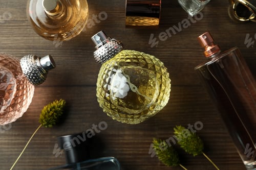 Preview: Bottles of perfumes on wooden background, top view and close up